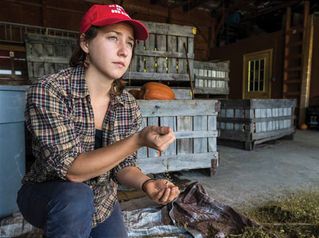 Student in a barn with produce